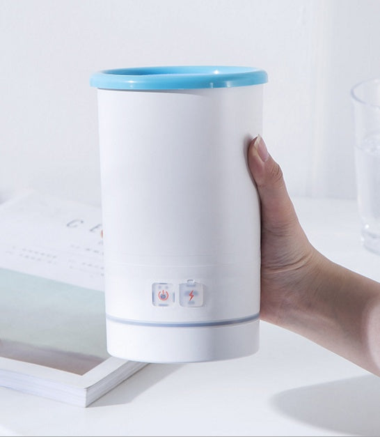 USB paw washing cup in a hand, portable foot cleaning device with blue top and buttons.